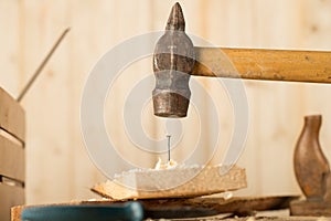 Big nail. A man in white gloves is hammering a big nail on the desk with black background. Shiny scrached hammer