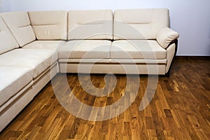 Big new beige sofa on wooden parquet floor