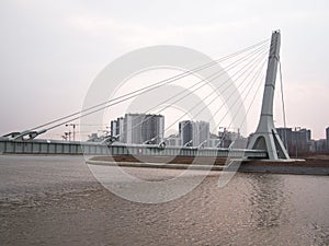 Big and new cable-stayed bridge hanging over the river on the background of buildings under construction