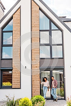 Big new house and african american couple standing near building