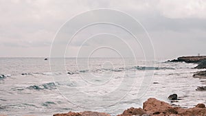 Big ocean waves crashing on rocky beach. Beautiful view of Mediterranean sea with rocky beach. Windy stormy ocean with big waves.