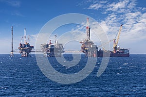 Big offshore oil rig drilling platform complex with anchored ship