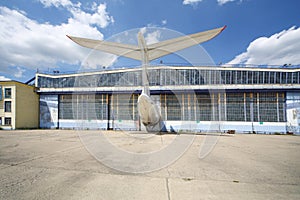 Big old battered aircraft hanger with protruding tail of plane