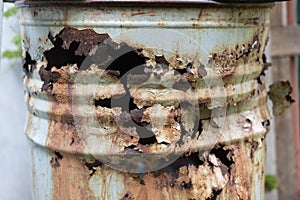 Big old rusty brown barrel with garbage with corrosion holes