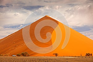 Big orange dune with blue sky and clouds, Sossusvlei, Namib desert, Namibia, Southern Africa. Red sand, biggest dun in the world.