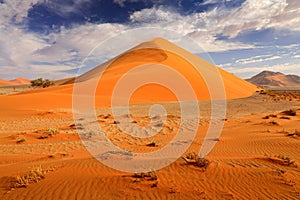 Big orange dune with blue sky and clouds, Sossusvlei, Namib desert, Namibia, Southern Africa. Red sand, biggest dune in the world