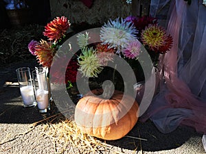 Big orange pumpkins on a pile of hay. Candles in tall glasses. Fall harvest of colorful squash. Composition with assorted raw