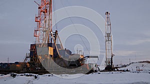 Big orange steel oil rig with annexes among snow landscape