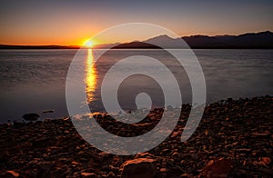 Big orange sun on sunrise sky. Morning lake landscape. Water reservoir Liptovska Mara, Slovakia