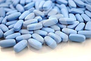 Big oval blue tablets closeup with sofl natural shadows and reflection on white background