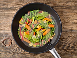 Big pan fried with colorful vegetables - peppers, peas, green beans, baby corn, carrots, beans. Colorful vegetarian lunch, top vie