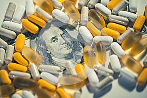 Big pharma conspiracy theory. Medical pills lying on top of US Dollar Bill