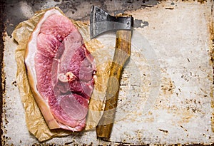 A big piece of raw pork with a meat axe.