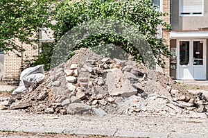 Big pile of cement concrete and dirt on the street in front of the residential building left as remains of the apartment renovatio