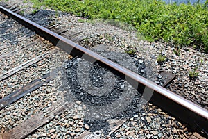 A big pile of coal spilled on the railroad tracks in Cape Breton Nova Scotia on a sunny day.