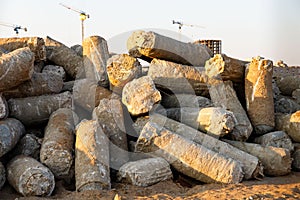 Close up of big pile of cut concrete piles at construction site, tower cranes on background