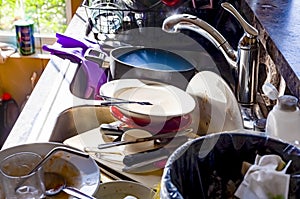 A big pile of dirty dishes, pots, utensils stacked into kitchen sink.