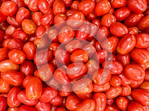 Big pile of fresh organic roma tomatoes at a farmers market produce stand