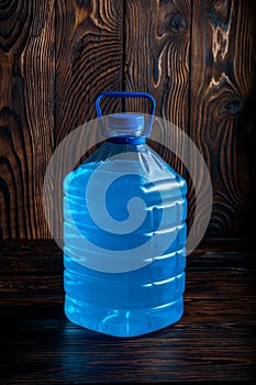Big plastic blue bottle on a dark wood background