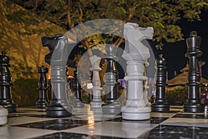 Big plastic chess pieces at hotel yard in evening. Chessboard game, strategy, ideas. Chess knight in center position