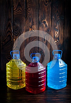 Big plastic colored bottles on a dark wood background