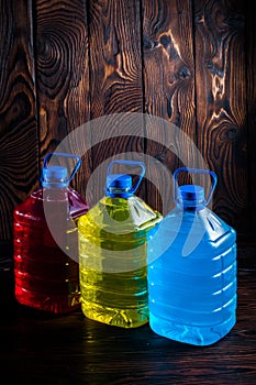 Big plastic colored bottles on a dark wood background