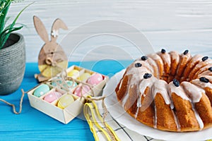 Big plate with cake and hand painted colorful eggs, on towel on blue background. Close up. Decoration for Easter,