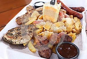 Big plate with delicious variety of meat - grilled steak, meatballs, chicken, sausages, bread and potato fries