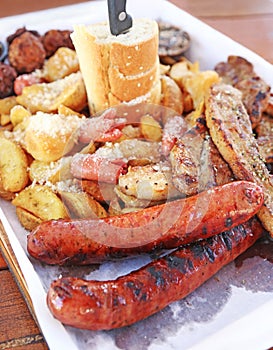 Big plate with delicious variety of meat - grilled steak, meatballs, chicken, sausages, bread and potato fries