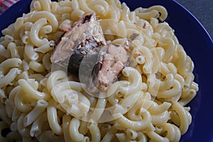 Big portion of pasta with fish on blue plate, close up shot. Macaroni with pilchard or sardine. Overeating, overweight concept