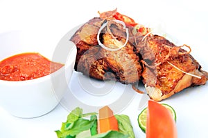 Big portion traditional fried chicken with spices on top of it, vegetable condiment, white background, not crispy fried chicken