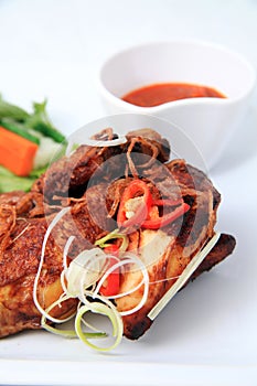 Big portion traditional fried chicken with spices on top of it, vegetable condiment, white background, not crispy fried chicken