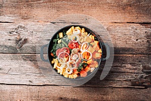 Big pot with sliced colorful vegetables and cooking utensils on rustic wooden background. Top view. Organic vegetarian ingredients