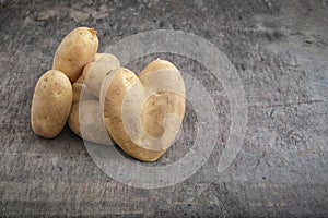 Big potatoes in shape of heart on rustic wooden table, concept of love to vegetables, valentine day food and cooking