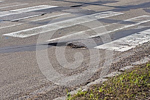 Big pothole, hole on road and green grass