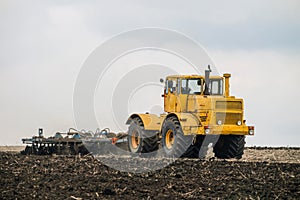 Big powerful wheeled tractor pulls the disc harrow