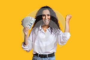 Big prize. Happy woman holding lots of money and shouting, orange background with free space