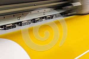 Big professional printer, processing a large scale glossy sheet of yellow paper rolls for color sampling.