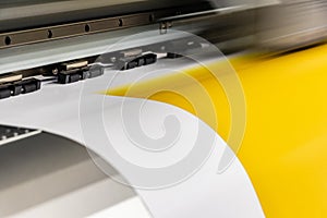 Big professional printer, processing a large scale glossy sheet of yellow paper rolls for color sampling. photo