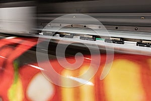 Big professional printer, processing massive vinyl red rolls.