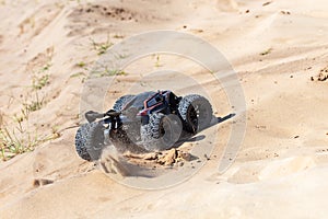 Big radio controlled buggy car driving fast and slipping on sand. RC toy moving fast on cross-terrain surface with dust