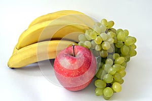 Big red apple in front of the bunch of bananas and ripe indian green grape isolated on white background.