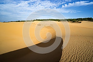 Big red dune on the background of blue sky.