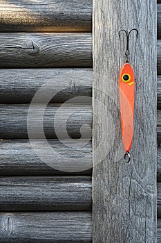 a big red fishing bait haning on a weathered grey fence photo