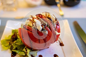 Big red french tomato served with fresh mozzarella cheese, basil pesto and creme balsamico as starter in restaurant in Provence,