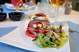 Big red french tomato served with fresh mozzarella cheese, basil pesto and creme balsamico as starter in restaurant in Provence,