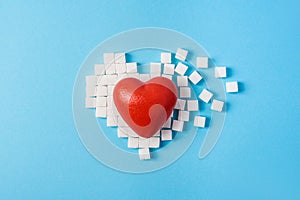 Big red heart on broken heart made of sugar cubes on a blue background