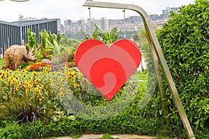 Big red heart hanging from an iron frame in the park