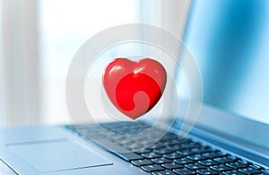 Big red heart on laptop keyboard. Valentine`s day holiday concept. Online love, remote communication on internet, social networks