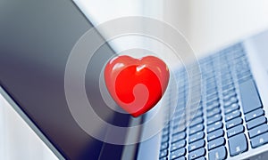 Big red heart on laptop keyboard. Valentine`s day holiday concept. Online love, remote communication on internet, social networks